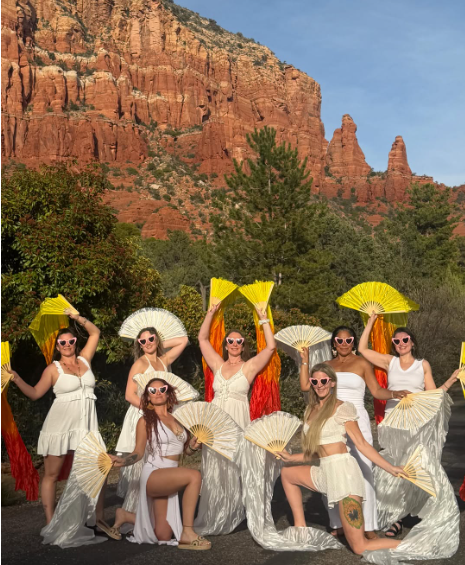 Christina's retreat group with golden fans beneath red rock cliffs
