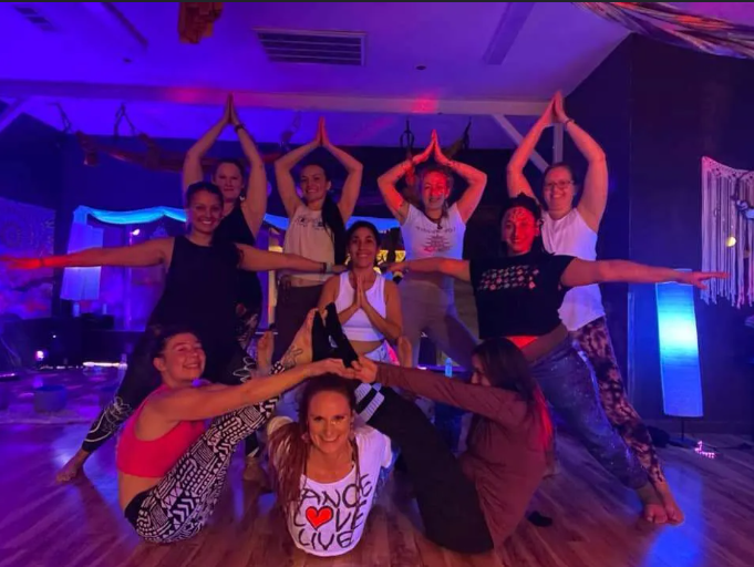 Smiling yoga group posing together under glowing lights