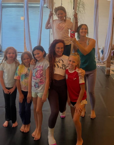 Christina and her kids' aerial class posing together in the lounge