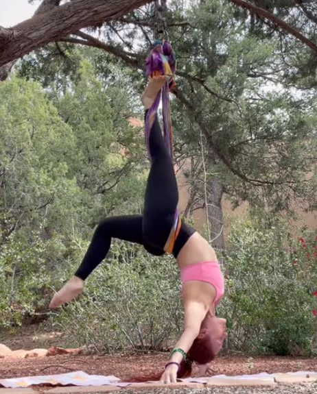 Christina inverting on aerial silks hung from a tree