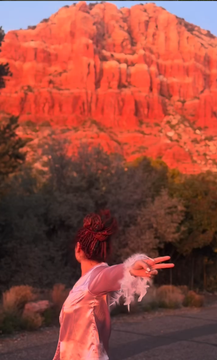 A dancer twirling beneath glowing red cliffs at sunset