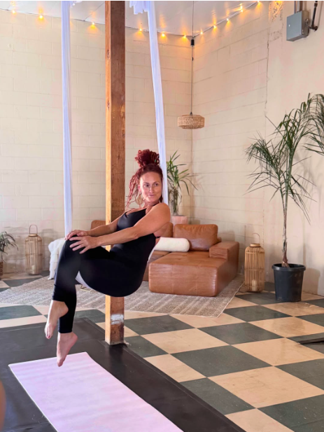 Christina floating in a white aerial hammock in the sunlit lounge
